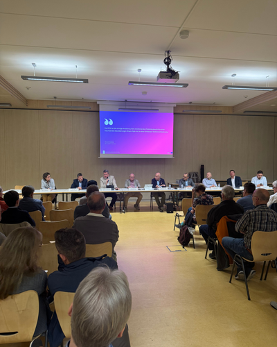 Menschen sitzen vor einer Präsentation in einem Raum