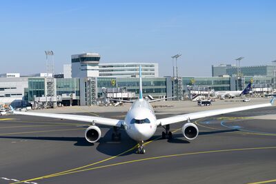 Frontansicht eines Flugzeugs, im Hintergrund der Frankfurter Flughafen